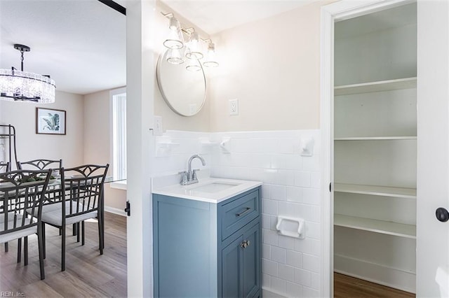 bathroom with vanity, tile walls, wood finished floors, and wainscoting