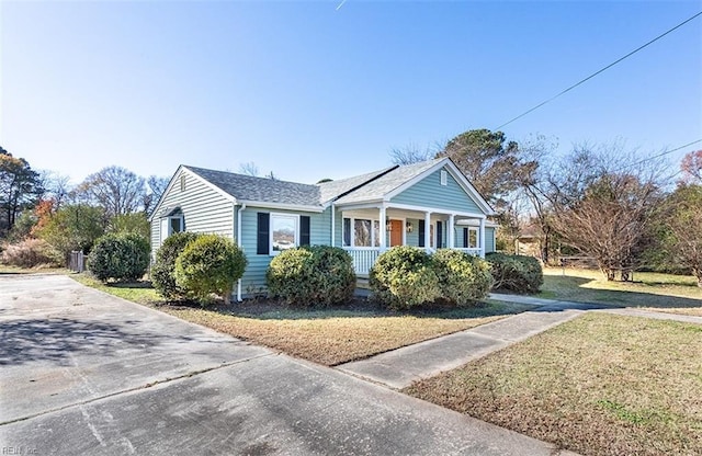 view of side of property featuring a yard, covered porch, and a shingled roof