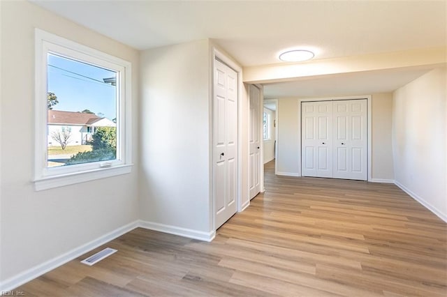 unfurnished bedroom with light wood-style flooring, baseboards, visible vents, and a closet