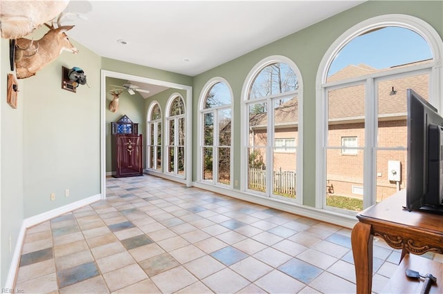 unfurnished sunroom with a ceiling fan