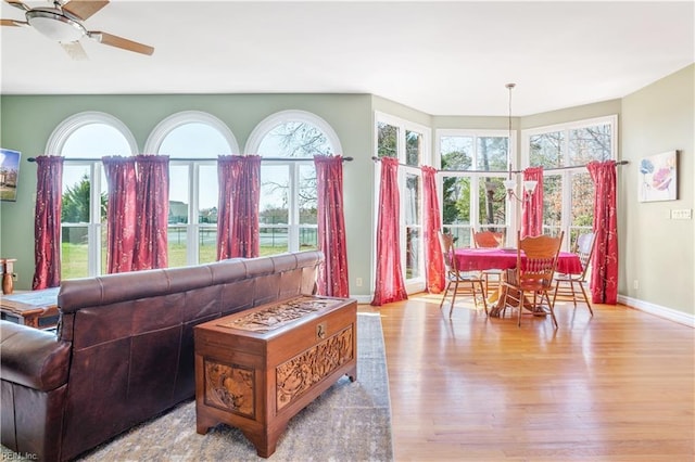 living room with a wealth of natural light, baseboards, wood finished floors, and a ceiling fan