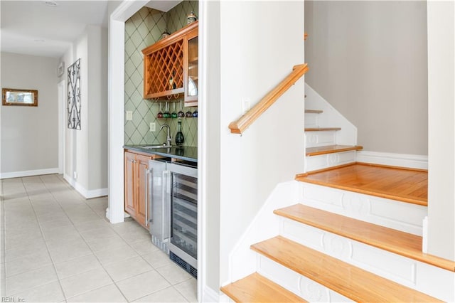 bar with beverage cooler, a sink, backsplash, stairway, and indoor wet bar