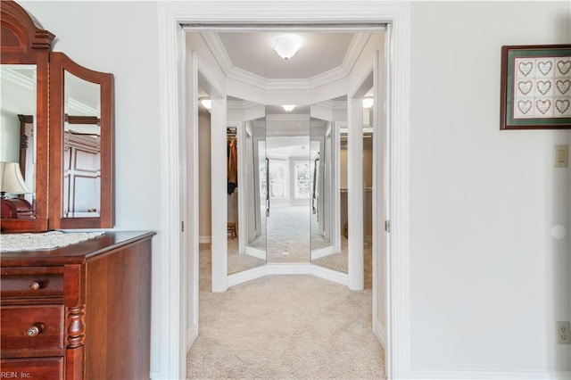 corridor with ornamental molding, baseboards, and light carpet