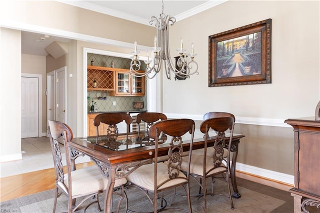 dining room with ornamental molding, light tile patterned flooring, baseboards, and a chandelier