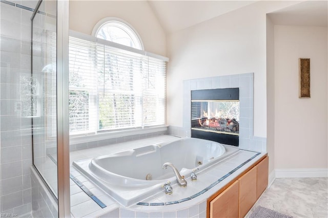 bathroom featuring lofted ceiling, baseboards, tiled shower, a whirlpool tub, and a tile fireplace