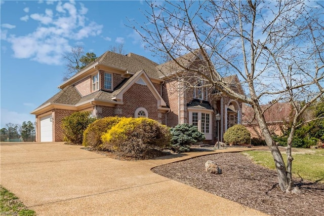 view of front of property with a shingled roof, concrete driveway, a front yard, an attached garage, and brick siding