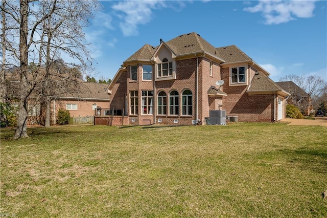 back of house with a garage, a yard, cooling unit, and brick siding