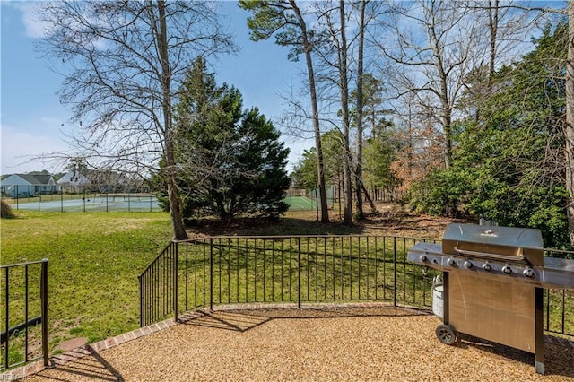 view of yard featuring a tennis court and fence