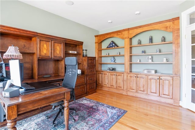 office space with built in shelves and light wood-style floors