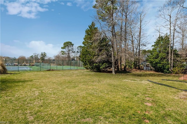 view of yard with a tennis court and fence