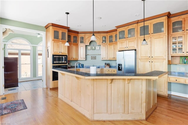 kitchen featuring a spacious island, dark countertops, light wood-style flooring, a kitchen breakfast bar, and black appliances