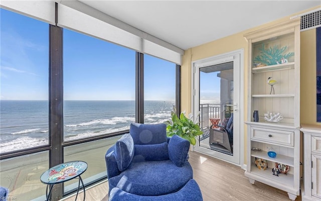 living area featuring a beach view, wood finished floors, and a water view