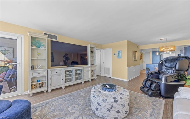 living area featuring visible vents, a notable chandelier, and wood finished floors