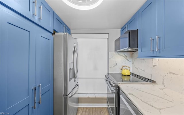 kitchen with wood finished floors, light stone countertops, stainless steel appliances, decorative backsplash, and blue cabinets