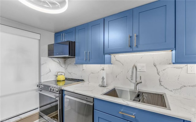 kitchen with decorative backsplash, blue cabinetry, appliances with stainless steel finishes, and a sink