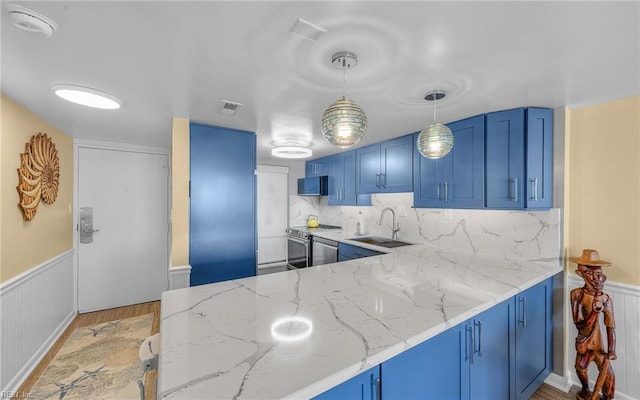 kitchen featuring blue cabinets, visible vents, a sink, light stone counters, and appliances with stainless steel finishes