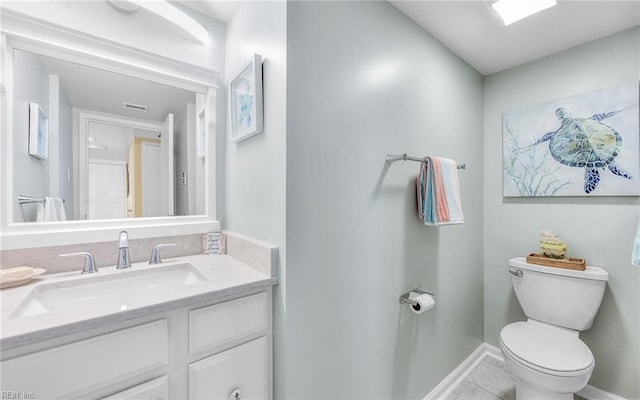 half bathroom featuring baseboards, toilet, and vanity