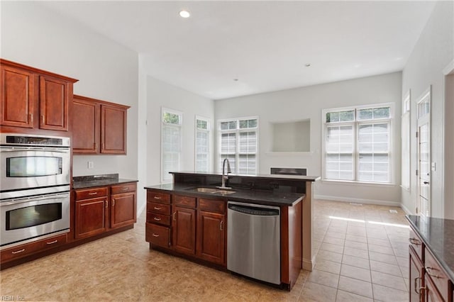 kitchen featuring a sink, dark stone counters, appliances with stainless steel finishes, light tile patterned floors, and baseboards