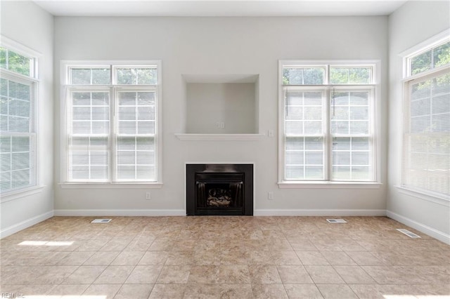 unfurnished living room with visible vents, baseboards, light tile patterned flooring, and a fireplace