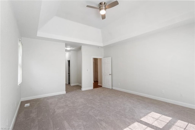 unfurnished bedroom featuring carpet flooring, ceiling fan, baseboards, and a tray ceiling