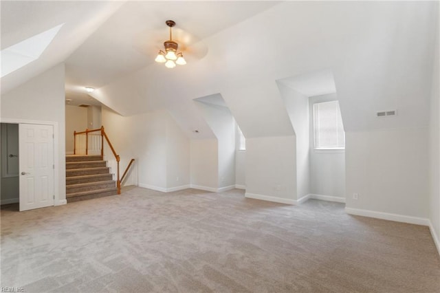 bonus room featuring baseboards, visible vents, carpet floors, stairs, and lofted ceiling with skylight