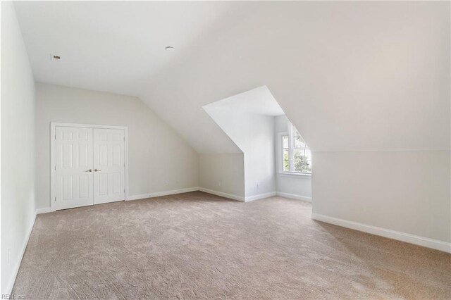 additional living space with baseboards, lofted ceiling, and carpet flooring