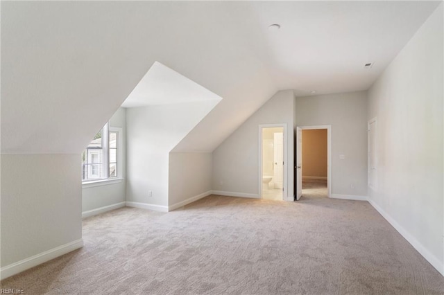 additional living space featuring baseboards, carpet flooring, and vaulted ceiling