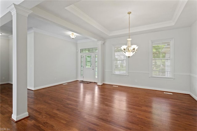 interior space with a tray ceiling, wood finished floors, ornate columns, and a chandelier