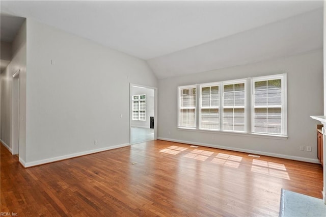 unfurnished living room with vaulted ceiling, plenty of natural light, and wood finished floors