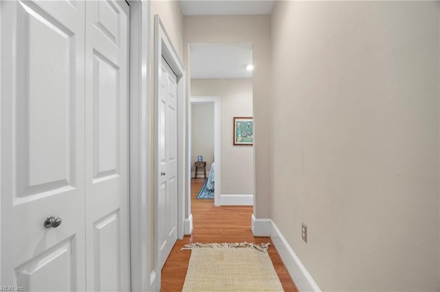 corridor with baseboards and wood finished floors