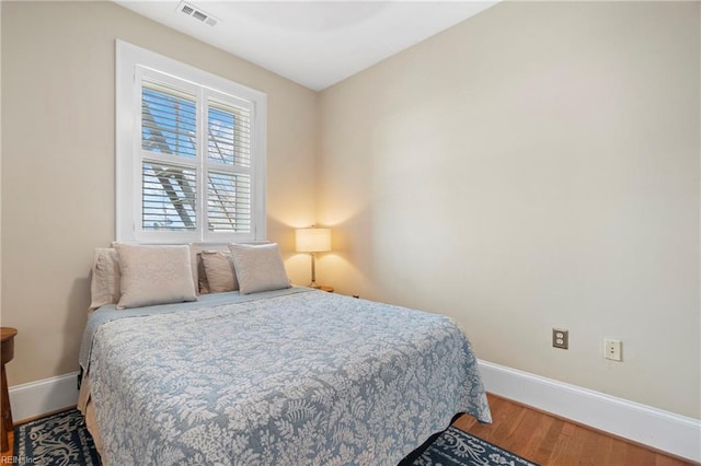 bedroom featuring visible vents, baseboards, and wood finished floors