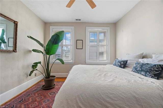 bedroom featuring visible vents, baseboards, wood finished floors, and a ceiling fan