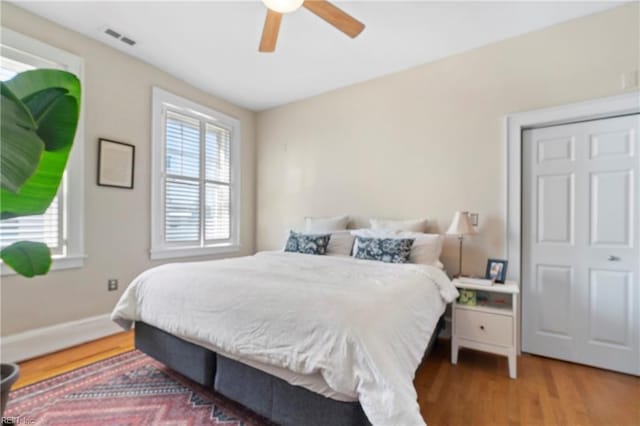 bedroom featuring ceiling fan, wood finished floors, visible vents, and baseboards