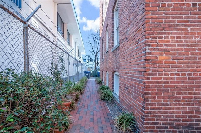 view of side of home featuring fence and brick siding