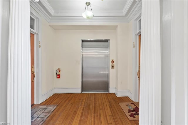 hall featuring elevator, hardwood / wood-style floors, baseboards, and ornamental molding