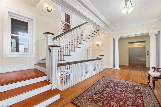 staircase with wood finished floors, elevator, ornamental molding, and ornate columns