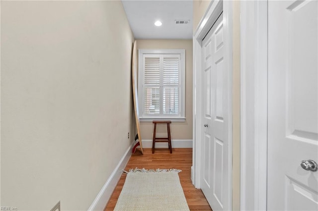 hall featuring visible vents, baseboards, and wood finished floors