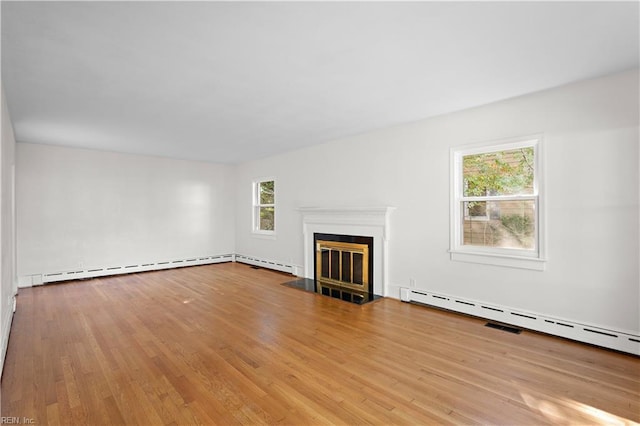 unfurnished living room featuring a baseboard heating unit, a fireplace with flush hearth, and wood finished floors