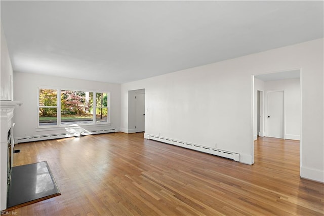 unfurnished living room featuring baseboard heating, a fireplace, and wood finished floors