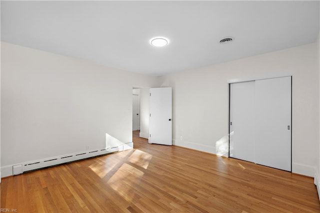 unfurnished bedroom with baseboards, visible vents, a baseboard radiator, light wood-style flooring, and a closet