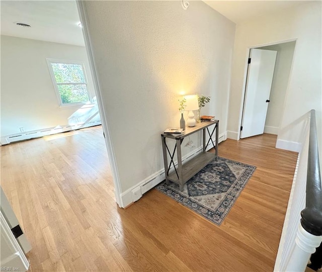 hallway with visible vents, baseboards, baseboard heating, and wood finished floors