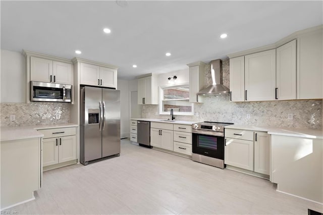 kitchen with backsplash, wall chimney range hood, light countertops, appliances with stainless steel finishes, and a sink