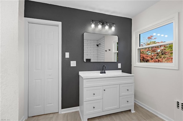 full bath with vanity, baseboards, and a closet