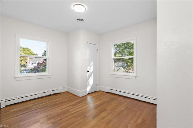 spare room with light wood-style flooring, baseboards, visible vents, and a baseboard radiator