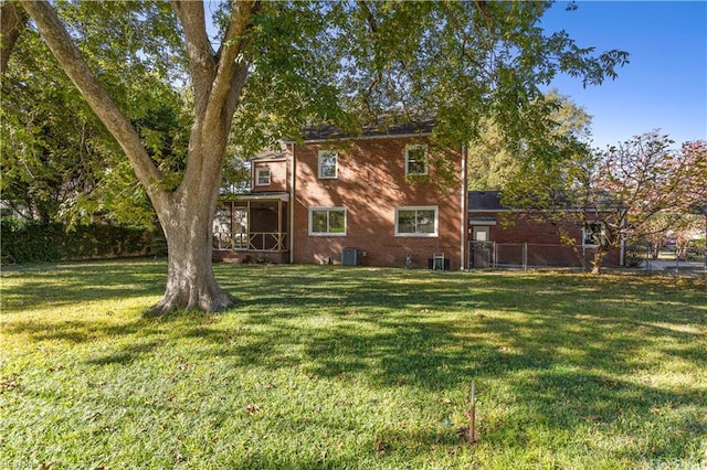 back of property featuring brick siding, central air condition unit, a yard, and fence