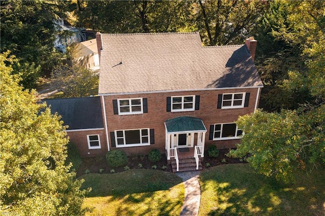 colonial home featuring a front yard, brick siding, and a chimney