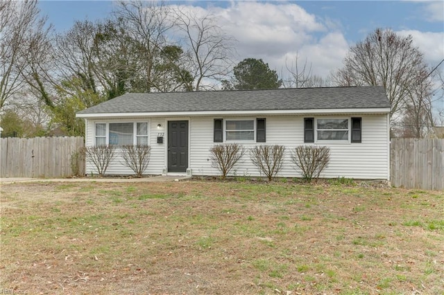 ranch-style house featuring a shingled roof, a front lawn, and fence