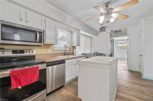 kitchen featuring visible vents, a sink, ornamental molding, appliances with stainless steel finishes, and dark wood-style flooring