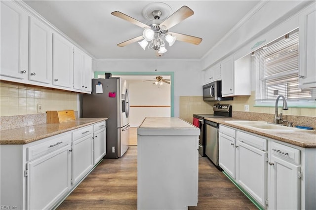 kitchen featuring a sink, stainless steel appliances, white cabinets, and a center island