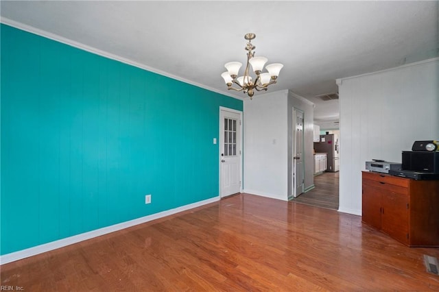 unfurnished dining area with visible vents, crown molding, baseboards, wood finished floors, and a notable chandelier